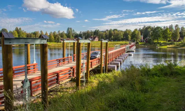 En bil kör över flottbron i Gagnef en solig dag.