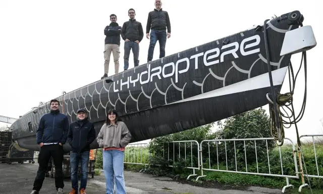 L'équipe pose fièrement devant l'hydroptère 2.0, un navire futuriste prêt à fendre les flots.