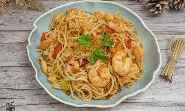 Delicioso plato de noodles con gambas, pimientos rojos y perejil fresco. Un festín para los sentidos.