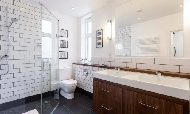 Baños modernos y reformados con plato de ducha, lavabo doble y mueble de madera.