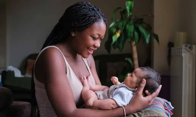 Eine junge Frau hält ihr Baby liebevoll im Arm. Die Frage "wie lange kann man stillen" beschäftigt viele Mütter.