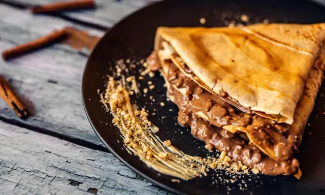 Crepe doblada con relleno cremoso de chocolate y trocitos de frutos secos. Una deliciosa receta crepes para disfrutar.