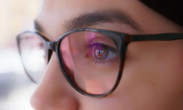 Zbliżenie oka w okularach, odbicie światła sugeruje, że optometrysta źle dobrane szkła.
