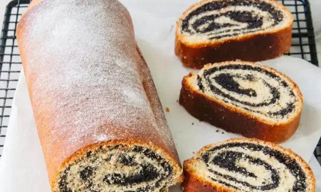 Stary przepis babci na makowiec. Puszysty, pachnący makowiec z cukrem pudrem, pokrojony na plastry, odsłaniający bogate nadzienie makowe.