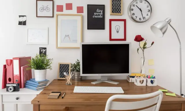 Bureau organisé pour une **optimisation** du travail : écran, clavier, plante verte, et décorations murales inspirantes.