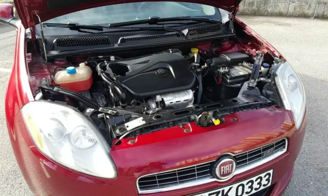 Czerwony Fiat Bravo 1.4 T-Jet z otwartą maską, widoczny silnik i reflektor.