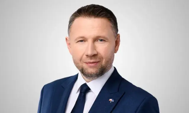 Mężczyzna w granatowym garniturze, z krótkimi włosami i zarostem, to minister spraw wewnętrznych.