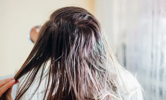 Nasse Haare, die nur mit Wasser gewaschen wurden, werden von einer Hand durchkämmt.