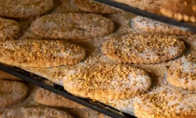 Varias cocas de llardons recién horneadas, cubiertas de azúcar y trocitos de frutos secos, listas para disfrutar.