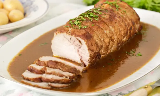Lomo de cerdo al horno en papel aluminio, jugoso y tierno, bañado en salsa y espolvoreado con perejil.