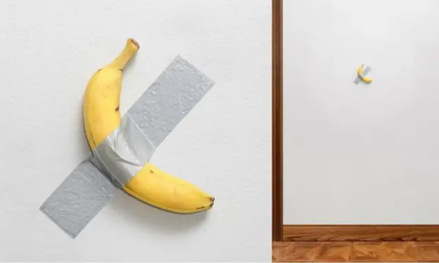 Un'opera d'arte banana, una gialla banana attaccata al muro con nastro adesivo grigio. A destra, un'altra banana, più piccola, fissata con nastro adesivo.