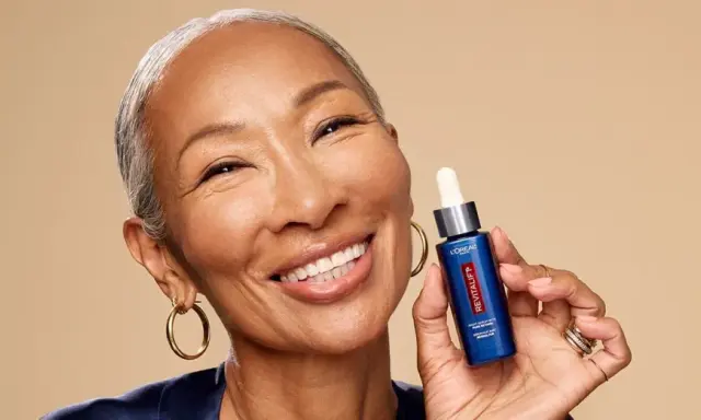 Mujer sonriente muestra un sérum Revitalift con retinol, ideal para rejuvenecer la piel y combatir arrugas.