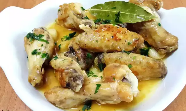 Alitas de pollo al ajillo, doradas y jugosas, servidas en una salsa con ajo y perejil fresco. ¡Un manjar irresistible!