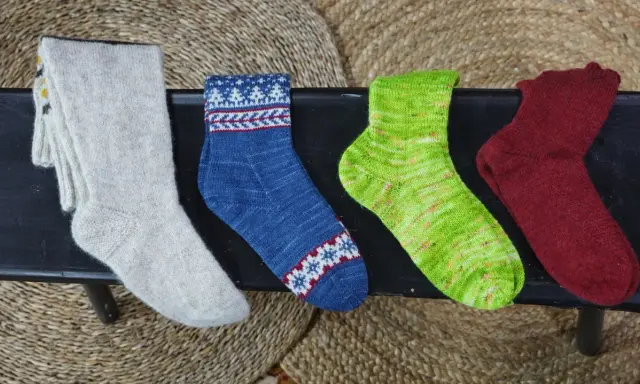 Fyra par handstickade sockor i olika färger och mönster. Perfekt för att sticka enkla sockor till barn.