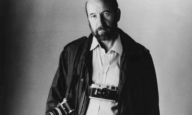 Ritratto di Gianni Berengo Gardin, fotografo con due macchine fotografiche al collo, sguardo intenso.