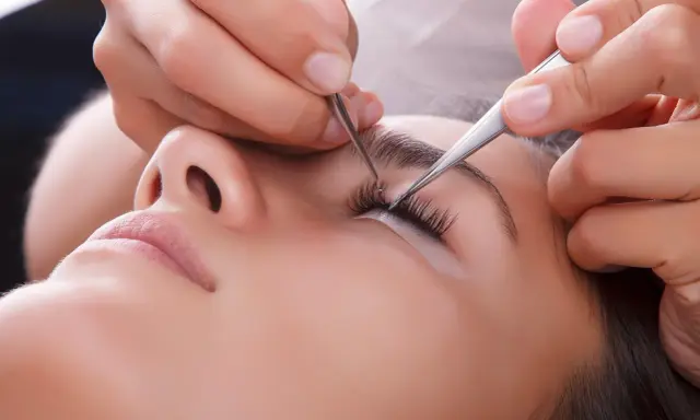 Pose de cils : quelle pince à épiler choisir pour un résultat parfait. Une esthéticienne applique des extensions de cils avec précision.