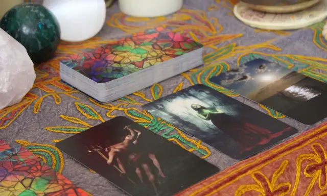 Tarot dzienny ryby: karty z mistycznymi obrazami, kryształ, kule i ozdobny obrus tworzą atmosferę wróżenia.