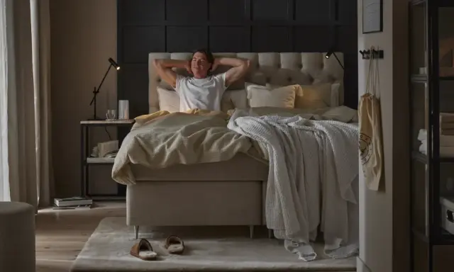 Man sträcker sig i en stor, inbjudande säng. En perfekt start på dagen för att sleepwell.