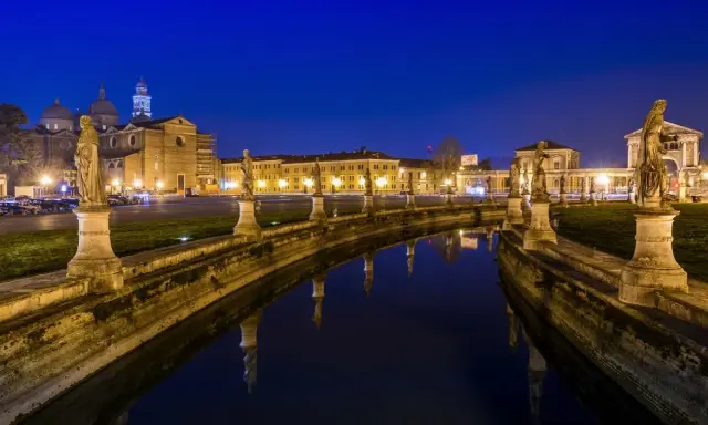 Prato della Valle di notte, un'idea di cosa vedere a Padova in un giorno. Statue e riflessi sull'acqua creano un'atmosfera magica.