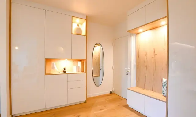 Ambiance chaleureuse dans cet intérieur de Kelt 550, avec des rangements blancs laqués et des niches en bois illuminées. Un miroir ovale ajoute une touche d'élégance.