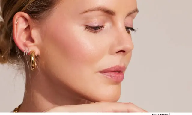 Profil d'une femme avec une peau éclatante, des boucles d'oreilles dorées et un maquillage subtil.