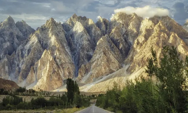 Droga w Karakorum Highway prowadzi przez surowe, skaliste góry oświetlone słońcem.