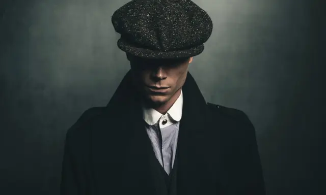 Mężczyzna w kaszkiecie i płaszczu, uosabiający styl lat 20. moda męska polska.