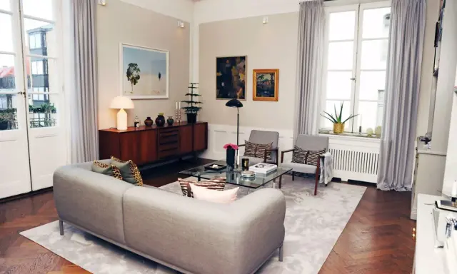 Ett modernt vardagsrum med en grå soffa, glasbord och konst. Johan Pråmell skulle trivas här.