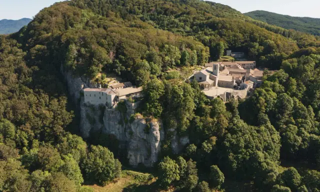 Il Santuario della Verna, incastonato tra i boschi, si erge maestoso su uno sperone roccioso. Un luogo di pace e spiritualità, meta di pellegrinaggi da Rimini e oltre.
