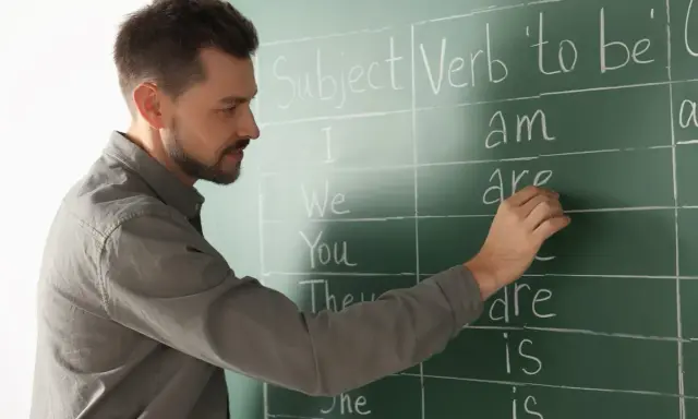 Nauczyciel pisze na tablicy "Subject", "Verb 'to be'". Przygotowanie do egzaminu z certyfikatem C1 angielski.