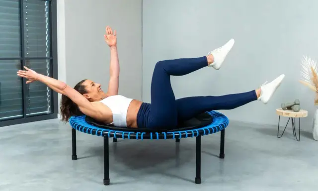 Frau macht ein intensives Workout auf einem Trampolin. Sie trainiert ihren Bauch, eine Übung, die man auch bei Tabata machen kann.