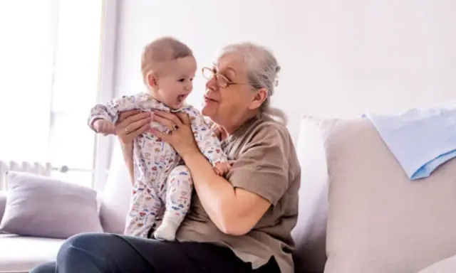 Abuela sonríe a su nieto varón, compartiendo un momento tierno. Ella tiene frases de amor para él.
