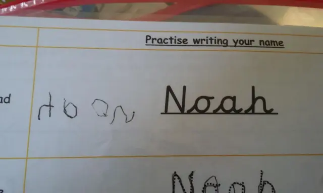 Siedmiolatek ćwiczy pisanie imienia "Noah" w lustrzanym odbiciu. Obok widać próbę pisania imienia.