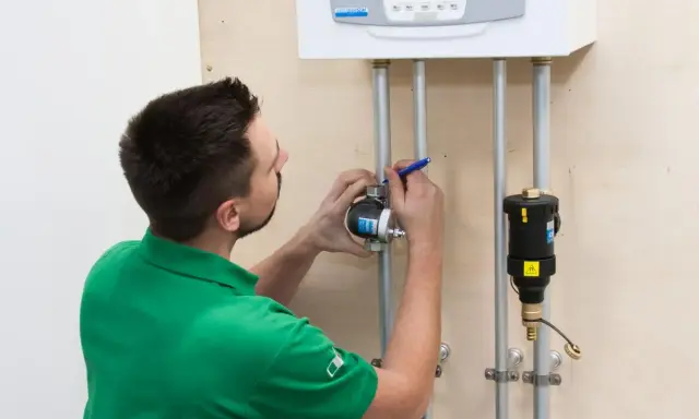 Instalator montuje separator zanieczyszczeń na rurze pod kotłem. Prawidłowe umiejscowienie zapewni ochronę systemu.