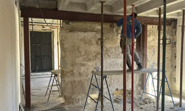 Trabajador realiza el empresillado de pilares en una obra. Se aprecian puntales metálicos y vigas de soporte.