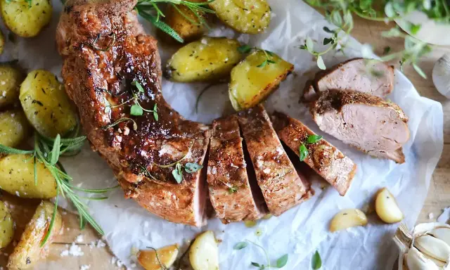 En saftig ytterfile i ugn, skuren i skivor, serverad med ugnsrostade potatisar, vitlök och färska örter.