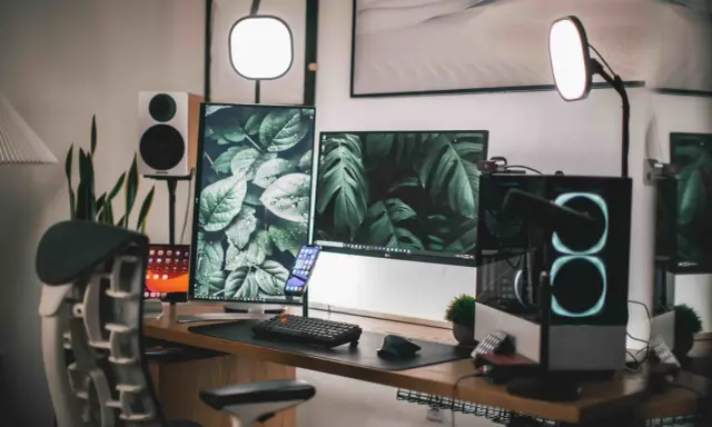 Escritorio moderno con doble monitor, PC con luces RGB, altavoces y plantas. Ideas para tu habitación gamer.