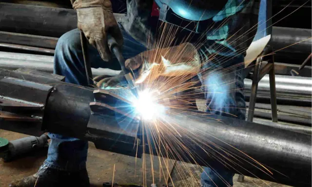 Un saldatore crea un legame forte, il vero significato del welding. Scintille luminose illuminano il metallo.