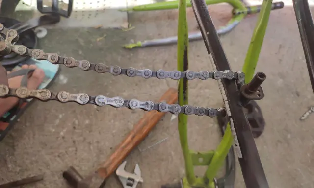 Narzędzia do naprawy roweru, w tym młotek i klucz, leżą obok rozpiętego łańcucha. Dowiedz się, jak rozpiąć łańcuch rowerowy bez spinki.