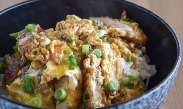 Oishi! Ein dampfendes Schüsselchen mit Reis, bedeckt mit knusprigem Hähnchen, Ei und Frühlingszwiebeln – ein Klassiker der japanischen Rezepte.