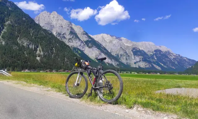 Rennrad für einen Alpencross, bereit für die Berge. Gepäcktaschen sind montiert, die Alpenkulisse ist atemberaubend.
