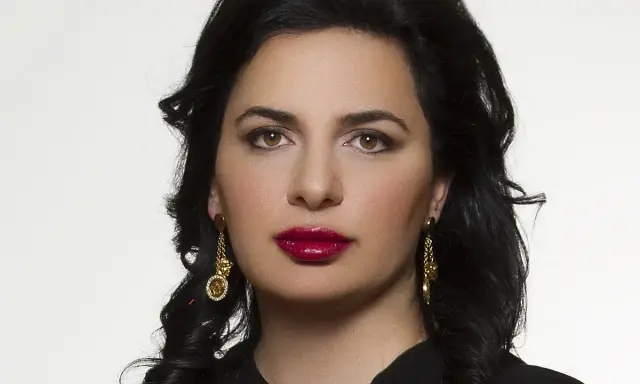 Portret Ruja Ignatova, kobiety o ciemnych włosach i wyrazistych ustach, w złotych kolczykach.