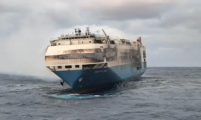 Le cargo Felicity Ace, en feu, dérive sur une mer agitée. De la fumée s'échappe de ses ponts supérieurs.
