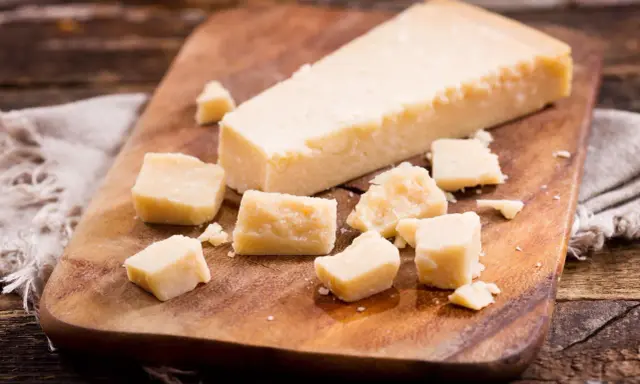 Parmesan-Stücke auf Holzbrett. So einfach kann parmesan einfrieren sein, um den Geschmack zu bewahren.