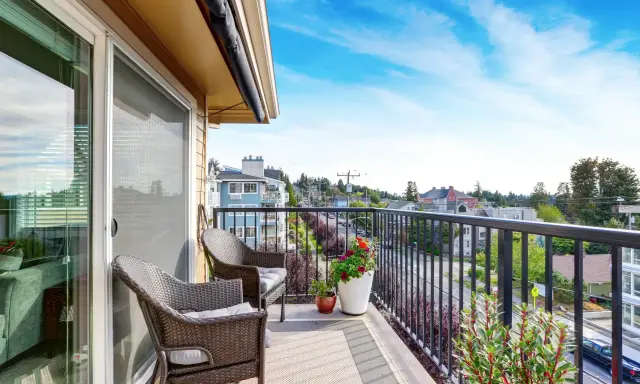 Wygodny balkon z rattanowymi meblami i kwiatami. Inspiracje na płytki na balkon.