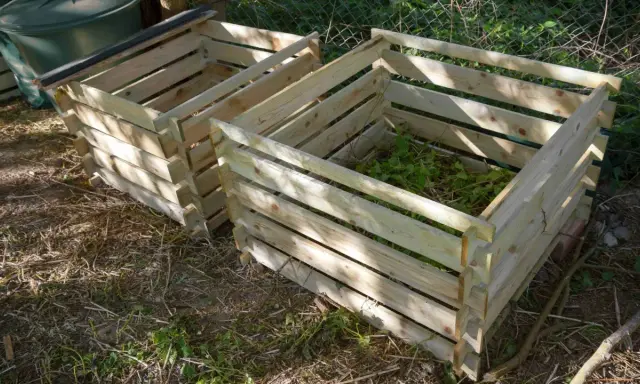 Deux composteurs maison en bois, l'un rempli de verdure, prêts à transformer les déchets de jardin en or noir.