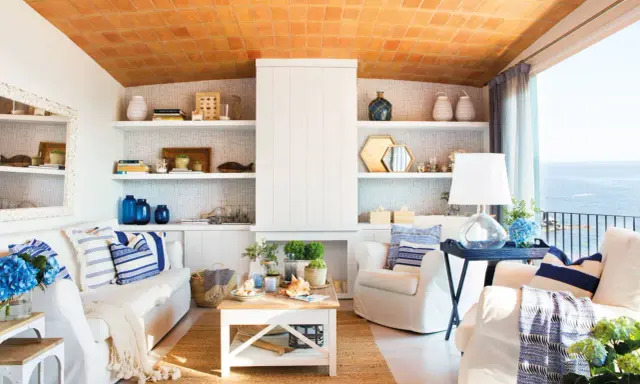 Salón con vistas al mar, decoración náutica y techo de tejas. Un espacio que evoca la sensación de estar en la playa en casa.