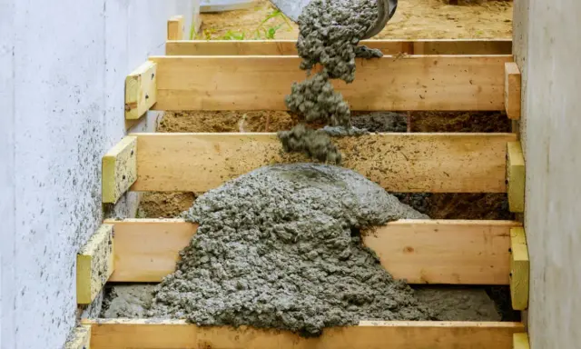 Vertido de hormigón fresco en el armado de una escalera de madera.