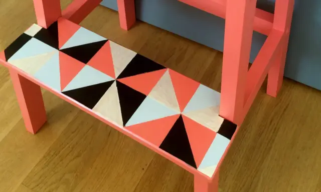 En pall med geometriskt mönster i orange, svart, vitt och ljusblått. Ett kreativt sätt att måla pall!