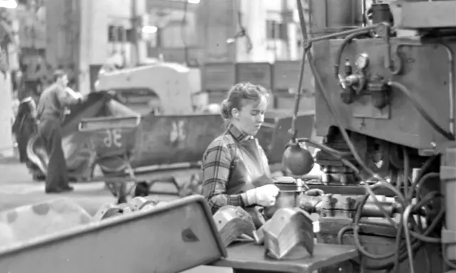 Kvinna arbetar vid maskin i fabriken, en del av arbetskraftsinvandring Sverige 1960.